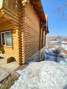 une cabane en rondins avec une terrasse couverte dans la neige dans l'établissement Сакский Двор, à Besqaynar