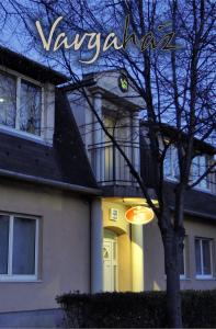 Varga-ház panzió في بوداورس: منزل أمامه شجرة