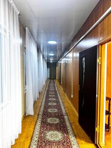 a long hallway with a rug on the floor and curtains at Гостиничный комплекс Bal-Meyir in Almaty
