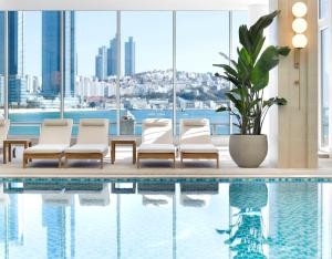 uma piscina num hotel com cadeiras e uma planta em The Westin Josun Busan em Busan