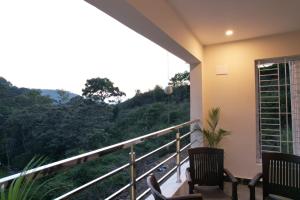 a balcony with two chairs and a view at Unique ajvi Resorts inn Yercaud in Yercaud