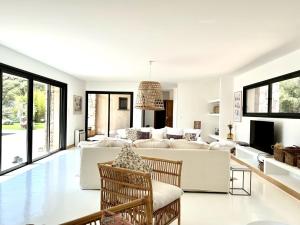 ein Wohnzimmer mit weißen Möbeln und großen Fenstern in der Unterkunft Villa Grenadier by Intendance Excellency in Cirendinu
