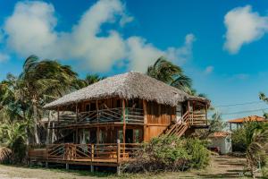 a bamboo hut with a thatched roof and palm trees at Vila Vento in Atins