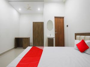 a bedroom with a white bed with a red blanket at OYO Flagship Hotel Rahul Service Appartment 2 in Nagpur