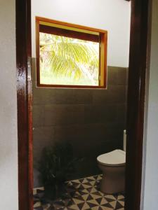 a bathroom with a toilet and a window at Air Manis Hillside Villa Cafe & Resto in Padang