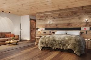 a bedroom with a large bed and a couch at Hotel Penzinghof in Oberndorf in Tirol