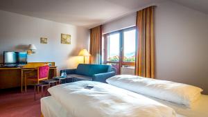 a hotel room with a bed and a couch and a window at Hotel Restaurant Lamm Hebsack in Remshalden