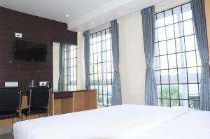 a bedroom with a large bed and large windows at FERN INN Kolkata in Kolkata