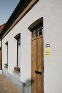 una puerta de madera en el lateral de un edificio blanco en Maison Patisson, en Kasterlee