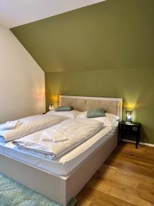 a large bed in a bedroom with a green wall at WELCOME HOTEL - Hellbühl in Hellbühl