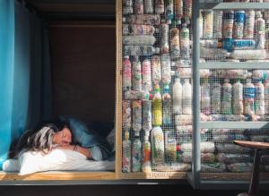 a woman is sleeping on a bed in a shelf of soda bottles at Amouter HC in Hengchun