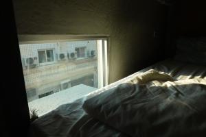 an unmade bed in a room with a window at Amouter HC in Hengchun