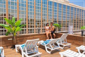 Dos mujeres en traje de baño sentadas en la terraza de la azotea en Dream Beach Hotel And Spa, en Tel Aviv