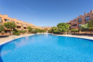 a large blue swimming pool with buildings in the background at Home2Book La Tejita Beach in Granadilla de Abona