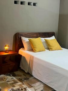 a bedroom with a bed with yellow pillows and a table at Le Jardin Arhumatic in Sambava