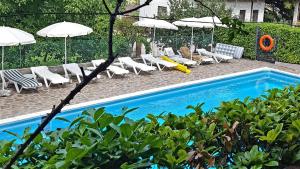 a swimming pool with lounge chairs and umbrellas at Lago di Garda Apartment in Peschiera del Garda