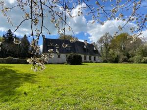 una casa vieja en un campo con un campo verde en Maison familiale pour des vacances nature en bord de mer à Bénodet en Clohars-Fouesnant