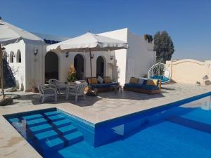 a swimming pool with chairs and a table next to a house at Encanto getaway in Sheikh Zayed