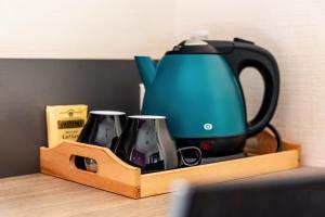 a tea kettle and two cups on a wooden tray at Le Bon Cap in Plurien