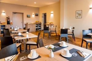 een restaurant met houten tafels en stoelen en een cafetaria bij Le Bon Cap in Plurien