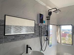 a shower in a bathroom with a sink and a tv at ME. Hotel in Louang Namtha