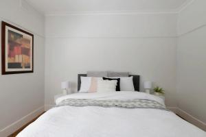 Dormitorio blanco con cama con sábanas y almohadas blancas en Inner city home West Footscray close to everything en Seddon