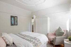 1 dormitorio blanco con 1 cama y 1 silla en Inner city home West Footscray close to everything en Seddon
