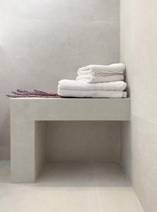 uma pilha de toalhas numa prateleira na casa de banho em Oinopia Apartments em Aegina Town
