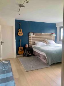 um quarto com uma cama e duas guitarras na parede em Appartement familial tt confort JO paris em Saint-Cloud