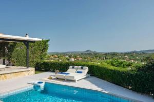 a swimming pool with a white couch and a chair next to a swimming pool at Sun Villa View in Lithakia