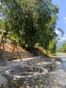 a stone wall next to a road with trees at Homestay Khoáng nóng Thông Nguyên in Nam Giang