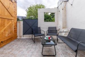 eine Terrasse mit Stühlen, einem Tisch und einer Holztür in der Unterkunft Le petit cocon in Levroux
