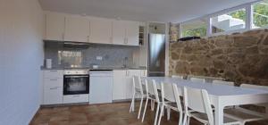 uma cozinha com uma mesa e cadeiras e uma parede de pedra em Casa Gil - AL em Valença