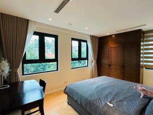 een slaapkamer met een bed, een bureau en ramen bij Muse Hanoi T-Place Apartment - Hoan Kiem Center in Hanoi