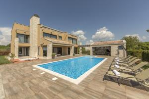 a house with a swimming pool and lounge chairs at Villa Verde in Vošteni