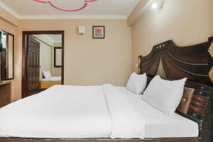 a bedroom with a large white bed with a wooden headboard at Kavi Home Stay in Mussoorie