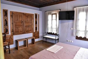 a bedroom with a bed and a chair and a window at Melina Hotel - Heritage in Poligiros