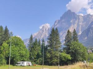 een camper geparkeerd in een veld voor een berg bij Appartamento Serdes C1 in San Vito di Cadore