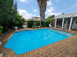 a large blue swimming pool with a tree in the background at Hill Manor Room 1 Self catering unit in Potchefstroom
