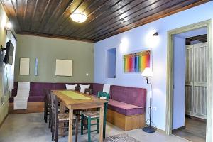 a dining room with a table and a purple couch at Melina Hotel - Heritage in Polygryos