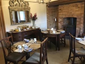 een eetkamer met houten tafels en een open haard bij White Hall Farm in Leamington Spa