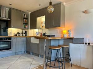 una cocina con armarios grises y taburetes de bar en Spacious and Bright Apartment, en Londres