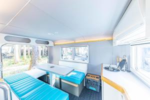 Zimmer mit einem Tisch und einem Schreibtisch in einem Wohnwagen in der Unterkunft glampark FREE AND EASY CAMP RESORT　三重県 in Komono
