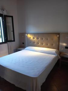 - une chambre avec un grand lit et des draps blancs dans l'établissement Agriturismo Villa Degli Ulivi, à San Vero Milis