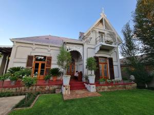a white house with potted plants on a yard at Hill Manor Room 1 Self catering unit in Potchefstroom +6 photos