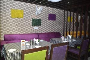 Hotel Shivlok International By BookingCare في Satna: غرفة طعام مع طاولتين وكراسي أرجوانية