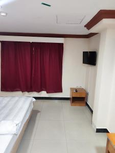 ein Schlafzimmer mit einem Bett und einem roten Vorhang in der Unterkunft Wings Grand Orchard Hotel in Kuala Lumpur