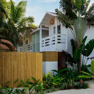 a house behind a fence with palm trees at Azora by Ayatana, Goa in Morjim