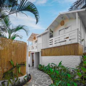 a white house with a fence and palm trees at Azora by Ayatana, Goa in Morjim