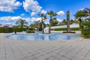 a swimming pool with palm trees and a clock tower at Rafol - Casa adosada con piscina comunitaria y tenis comunitario in Calpe